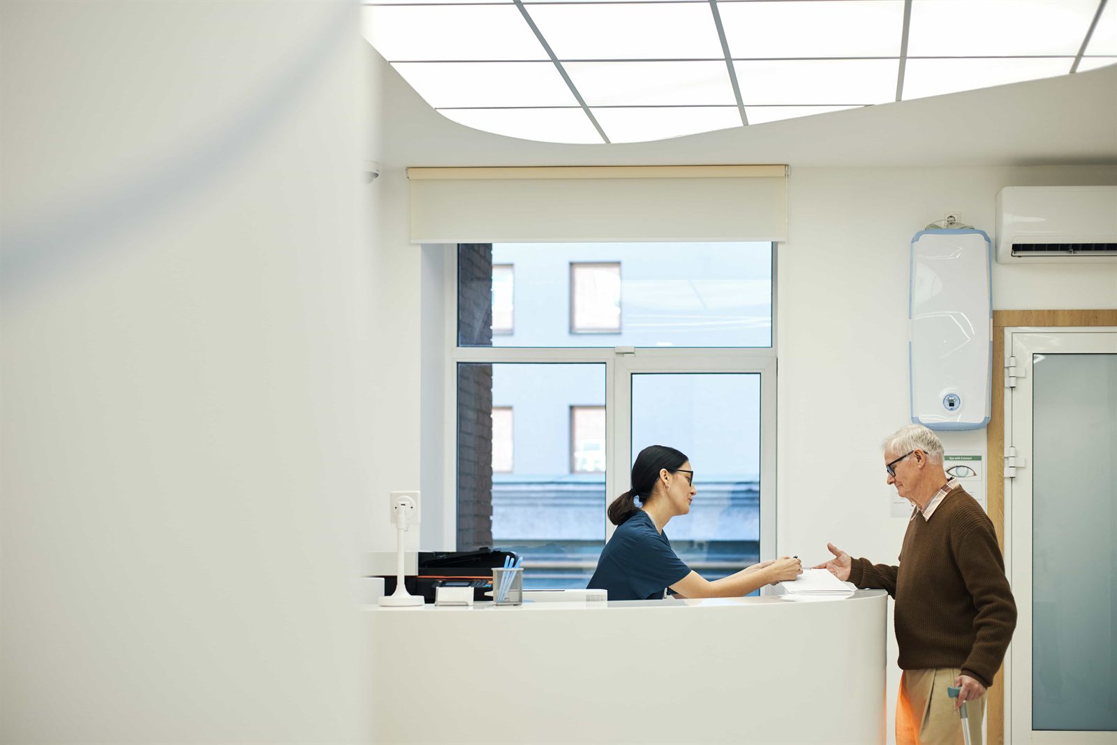 The bright reception at Juniper Dental Studio, with a patient checking in at the front desk